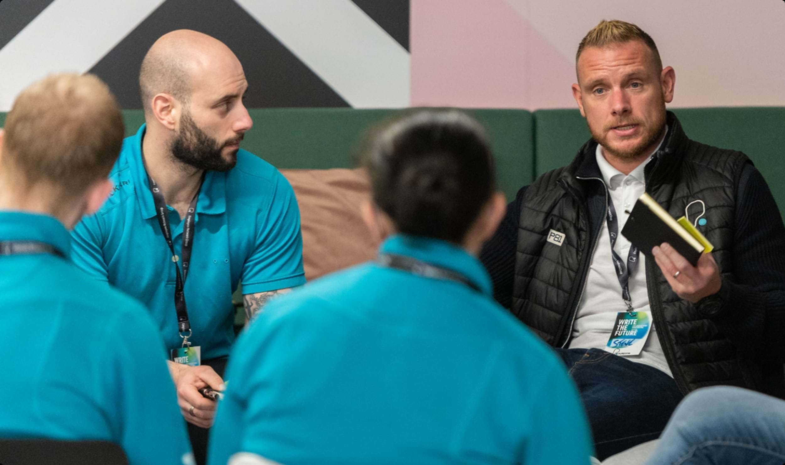 A man speaks to a group of colleagues during a collaborative workshop or training session.