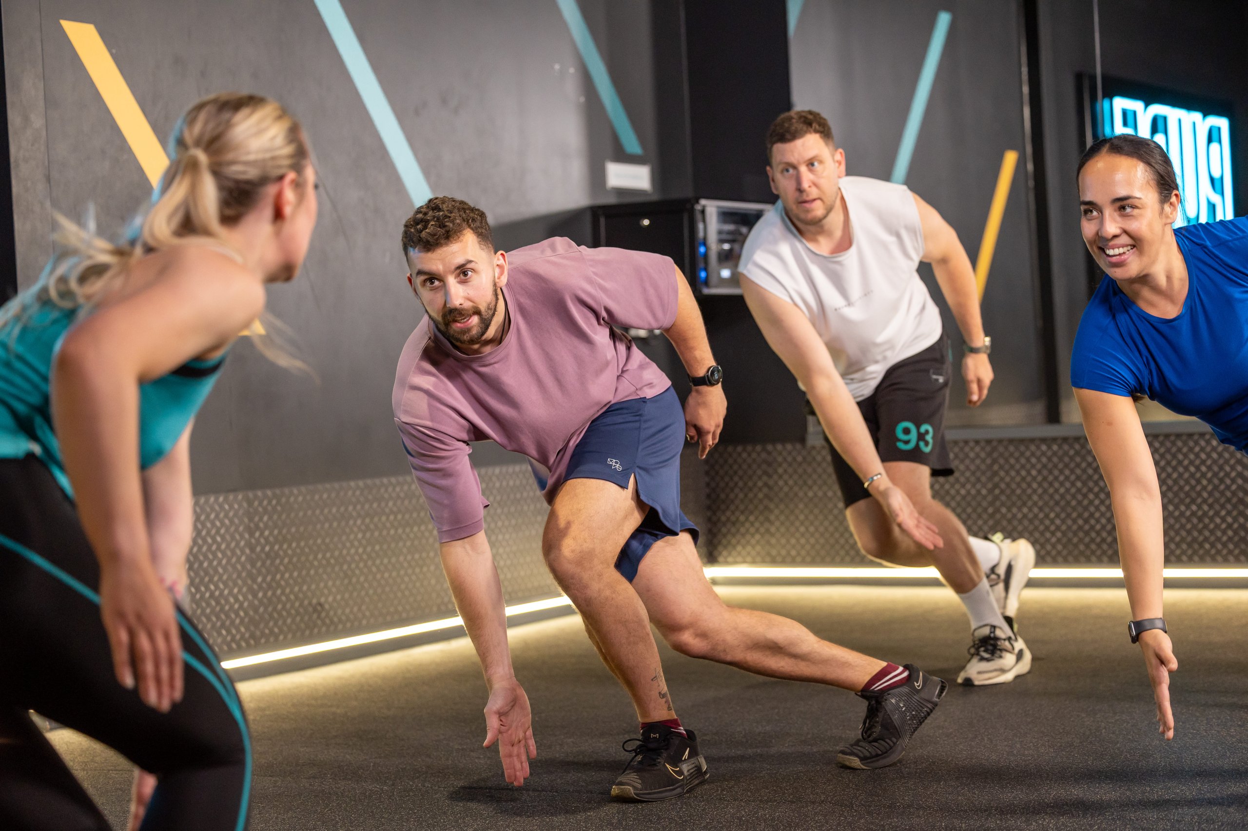 A group of people exercising with a trainer in a modern gym setting.