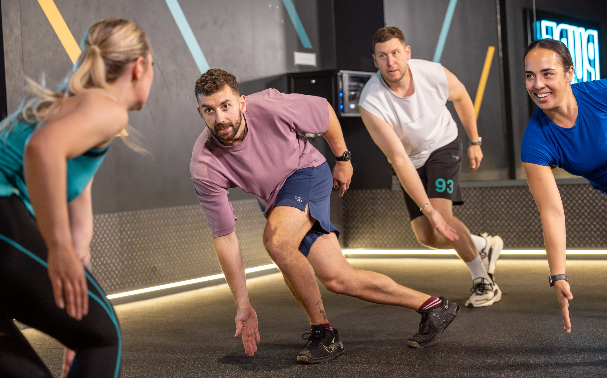 A group of people exercising with a trainer in a modern gym setting.